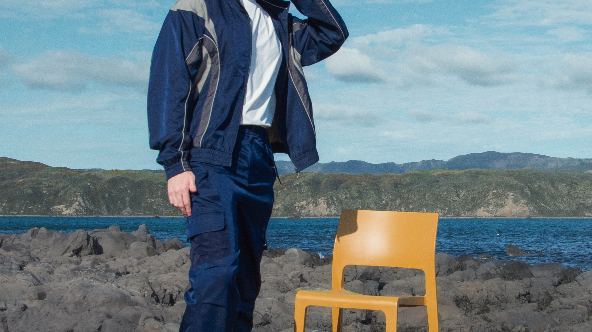 Man wearing a lightweight windbreaker standing by the coast, showcasing TSAN Apparel’s modern transitional jacket inspired by city and nature.