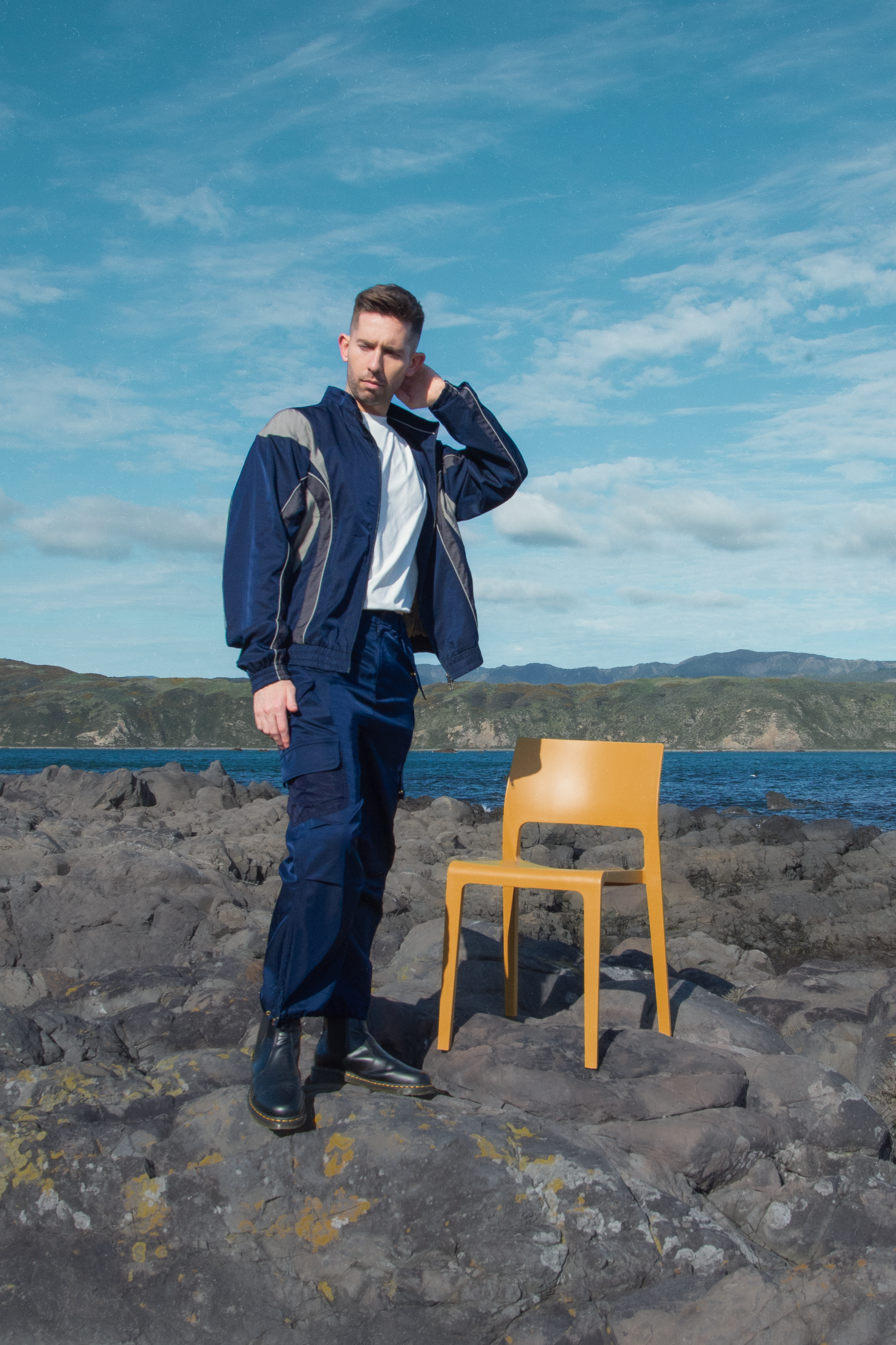 Man wearing a lightweight windbreaker standing by the coast, showcasing TSAN Apparel’s modern transitional jacket inspired by city and nature.